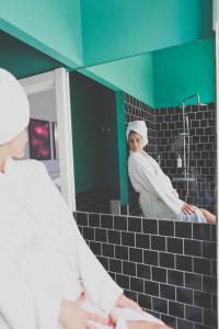 een vrouw kijkt naar zichzelf in een badkamerspiegel bij Esqina Urban Lodge in Lissabon