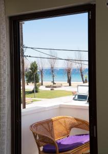 a glass door with a chair and a view of the water at Park Apartment in Paralia Dionysiou