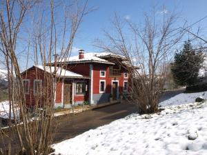 uma casa vermelha com neve no chão em Casa Rural Alborada em Bobia de Arriba