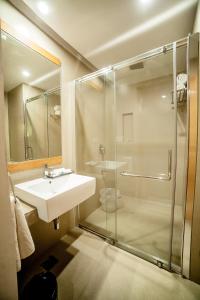 uma casa de banho com um lavatório e um chuveiro em Hotel Vivera Grande em Dindigul