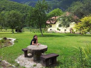 una mujer sentada en una mesa de picnic en un parque en Apartments and rooms Oasis of peace, en Bovec