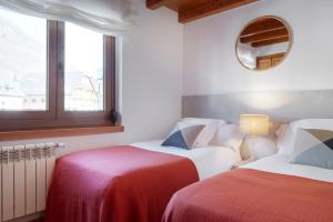 2 Betten in einem Zimmer mit Spiegel und Fenster in der Unterkunft Ribaeta by FeelFree Rentals in Vielha e Mijaran