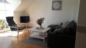 ein Wohnzimmer mit einem Sofa, einem Tisch und einem TV in der Unterkunft OstseeNest in Schönhagen