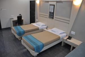 a room with two beds and a desk at Lotus Hotel in Solapur