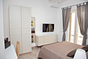 ein Schlafzimmer mit einem Bett und einem TV an der Wand in der Unterkunft Maison Lumière in Salerno