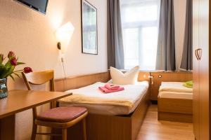 Zimmer mit 2 Betten, einem Tisch und einem Schreibtisch in der Unterkunft Pension an der Pillnitzer Schlossfähre in Dresden