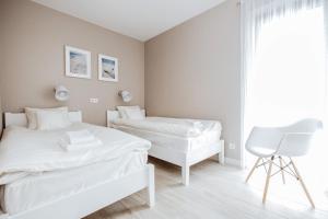 biała sypialnia z 2 łóżkami i krzesłem w obiekcie Apartment No. 1 - Vento Apartamenty we Władysławowie