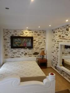 a bedroom with a bed and a stone wall at Sea&Stone Apartment in Skala Sotiros