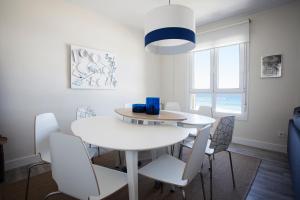 una sala da pranzo bianca con tavolo e sedie bianchi di Pacific - Iberorent Apartments a San Sebastián