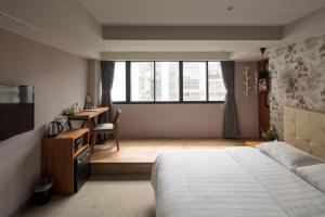 a bedroom with a bed and a desk and a window at Urtrip Hotel in Taipei