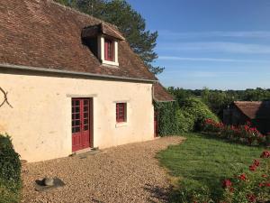 a cottage with a red door and a yard at Gîte De Serre in Le Grand-Pressigny