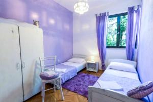 a room with two beds and a window with purple curtains at Apartment Dunja in Supetar