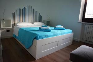 a white bed with blue sheets and pillows on it at Lucky's Home in Enna