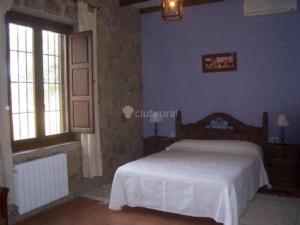 a bedroom with a bed in a room with blue walls at Casa Rural El Nido del Cuco in Valdeobispo