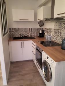 eine Küche mit weißen Schränken und einer Waschmaschine in der Unterkunft Appartement Côté Bassin in Andernos-les-Bains
