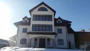 ein weißes Haus mit einem Hund im Schnee in der Unterkunft Willa Ostoja in Rabka-Zdrój