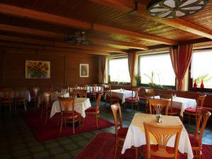 a dining room with tables and chairs and windows at Gasthof Hochsteg in Finkenberg