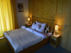 a bedroom with a bed with pillows and two lamps at Gasthof Hochsteg in Finkenberg