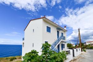 a white house with a blue staircase next to the ocean at Kimothoy in Armenistis