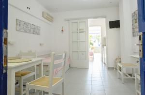a white dining room with a table and chairs at Nissos Poros in Poros