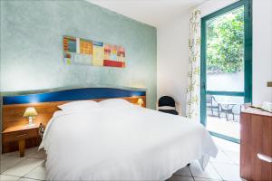 Un dormitorio con una gran cama blanca y una ventana. en Hotel La Villetta, en Fiumicino