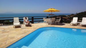 a woman sitting in a chair next to a swimming pool at Pousada Gente Bonita Mirante in Búzios