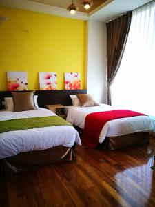 two beds in a room with yellow walls and wood floors at 198紅帽民宿l市區l電梯l停車場 in Magong