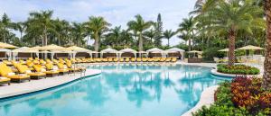 a beach with a pool, chairs, tables and umbrellas at Trump National Doral Golf Resort in Miami