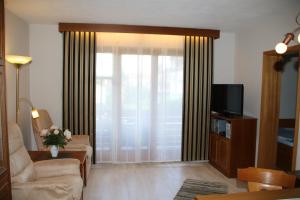 a living room with a couch and a tv at Landhaus Vogelweide - 2 Zimmer mit Balkon in Bad Füssing