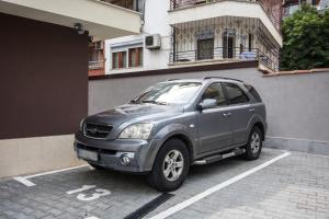 a gray suv parked in a parking lot next to a building at Domus Apartments City Center in Plovdiv