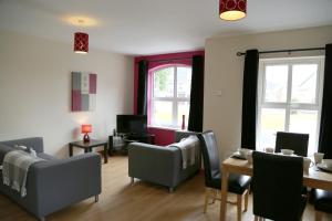 uma sala de estar com sofás, uma mesa e janelas em Millstone Park Apartment em Portstewart