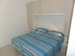 a bed in a white room with a blue blanket at Condominio Quasar in Bibione
