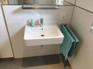 baño con lavabo blanco y toalla verde en Apartment unter den Weinbergen en Königswinter