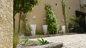 un giardino con vasi bianchi pieni di fiori e piante di Châteaux Demeures Vallée de L'Arc a Trets