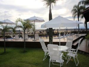 弗洛里亚诺波利斯Posada Sueños De Verano的泳池旁边有一张桌子，上面摆放着白色的椅子和遮阳伞