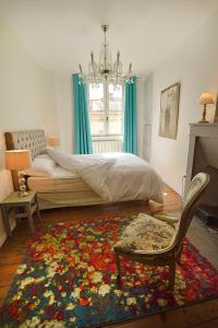 um quarto com uma cama, uma cadeira e um tapete em Les Apparts du Plot em Le Puy-en-Velay