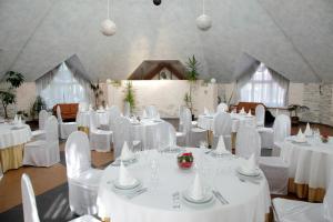 Knyazhyi Dvir في Knyazhichi: غرفة مليئة بالطاولات البيضاء والكراسي مع طاولة بيضاء