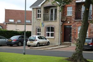 a white car parked in front of a brick house at Millstone Park Apartment in Portstewart