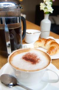 a cup of coffee on a table with a plate of bread at The White Lion Hotel in Aldeburgh