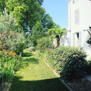 un jardin à côté d'une maison plantée d'arbres et de buissons dans l'établissement La Bastide des Songes - Demeure d'hôtes, à Robion