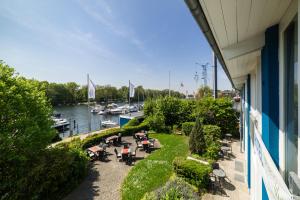 einen Balkon mit Tischen und Stühlen sowie einen Yachthafen in der Unterkunft Hotel Spree-idyll in Berlin