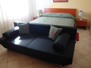 a black couch in a bedroom with a bed at Apartments Mogorović in Mošćenička Draga
