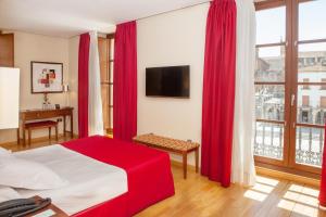 a bedroom with red curtains and a bed with a television at Soho Boutique Casa Don Fernando in Cáceres