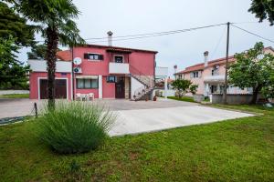 un edificio rosso con una palma di fronte di Apartments Roko a Rovigno (Rovinj)