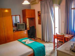 a room with a bed and a desk and a television at Aggelos Studios in Panormos Kalymnos