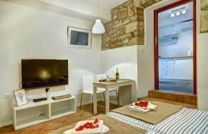 a living room with a television and a table with chairs at Apartman Amfiteatar Franko in Pula