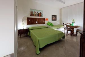 馬泰拉的住宿－La Quintessenza，一间卧室配有一张绿色的床和一张桌子