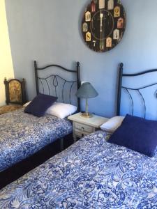 a bedroom with two beds and a clock on the wall at Apartamento Turísticos Luar 3 in El Rasillo