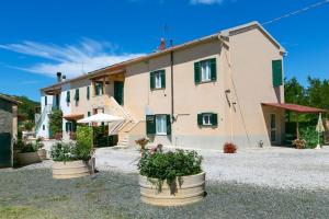 una casa con tre piante in vaso davanti di Agriturismo Case Nuove a Castellina Marittima