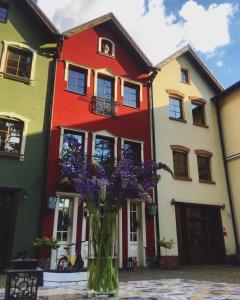 a vase of purple flowers in front of a building at Hotel oraz domy - Kanu Club in Nowy Zyzdrój